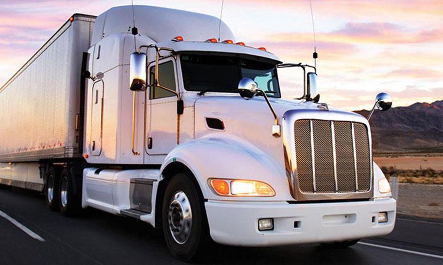 White semi truck on highway with sunrise